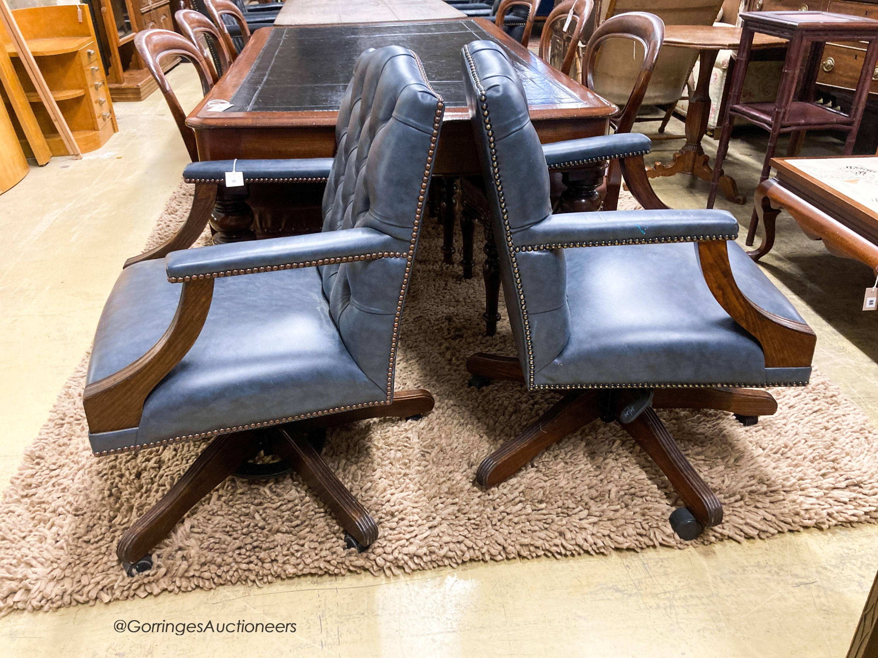 A pair of reproduction beech buttoned blue leather swivel desk chairs, width 60cm, depth 55cm, height 90cm